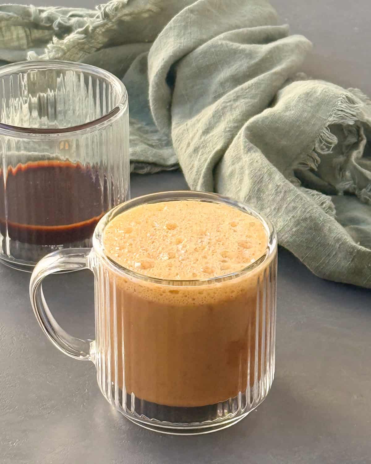 A glass mug with pumpkin spice latte in it.