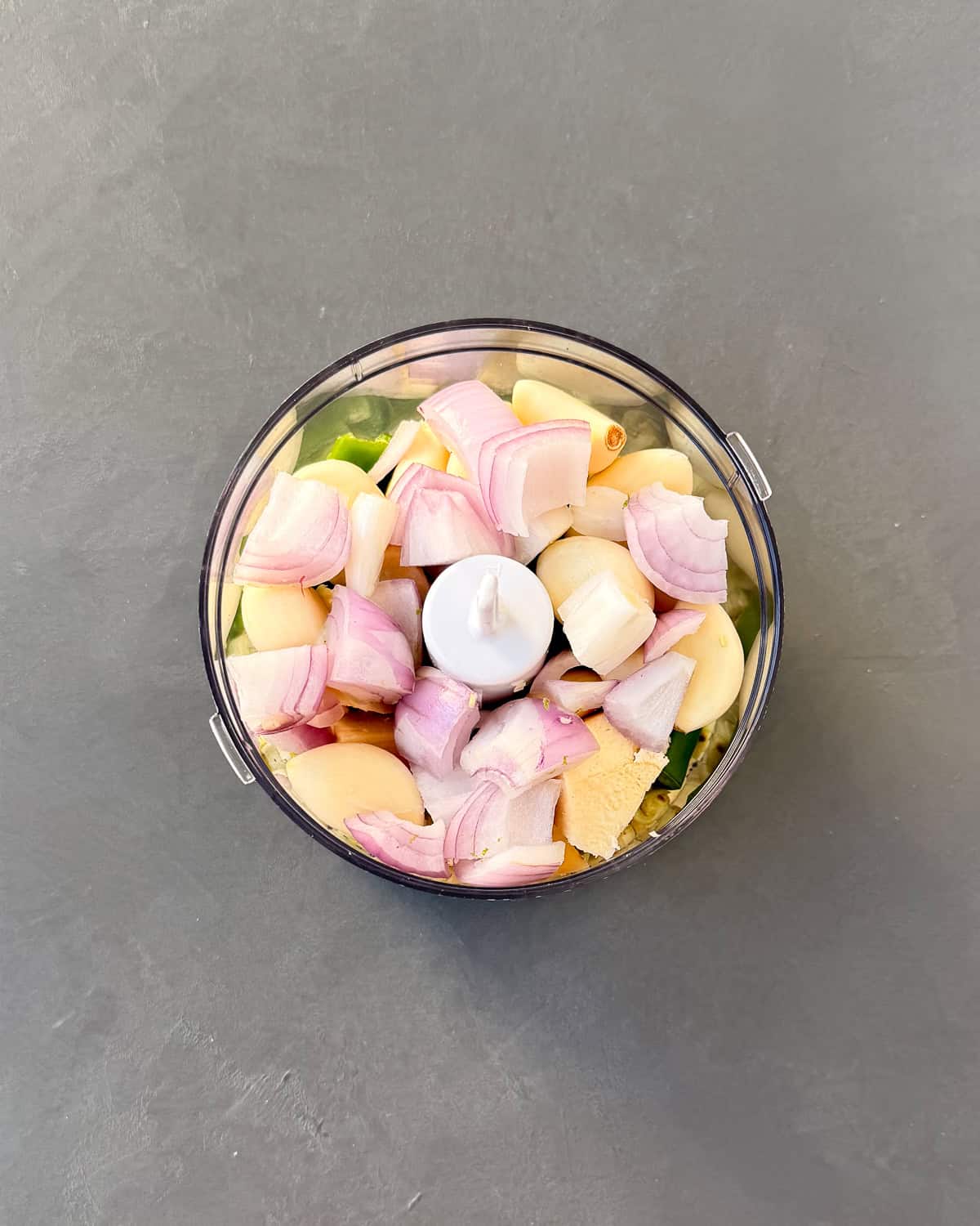 All lemongrass paste ingredients chopped up into a food processing bowl.