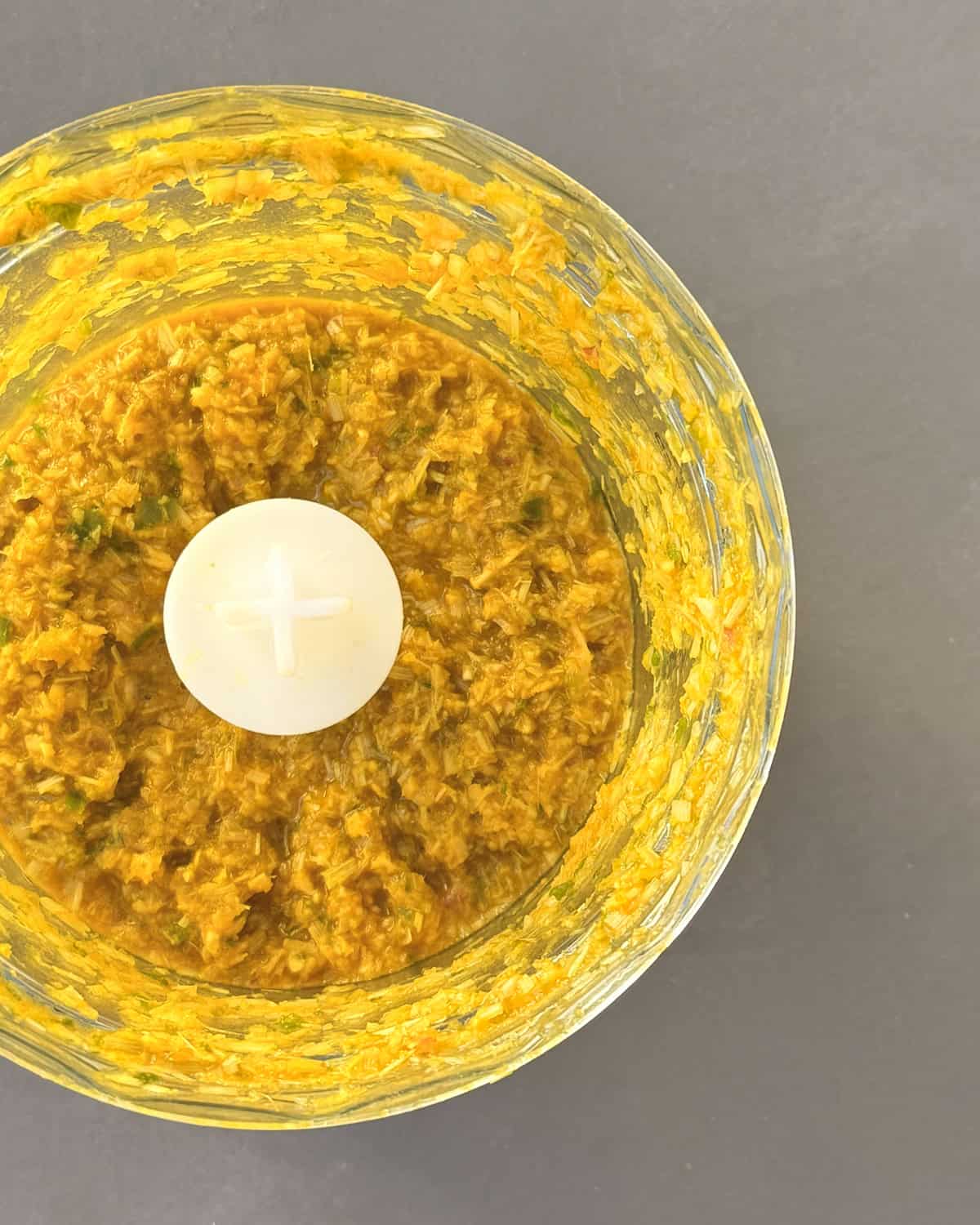 Finely processed lemongrass paste in a food processing bowl.