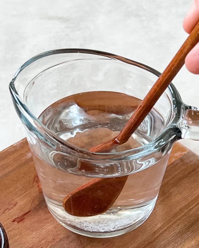 Quick pickle brine mixture in a jug with wooden spoon.