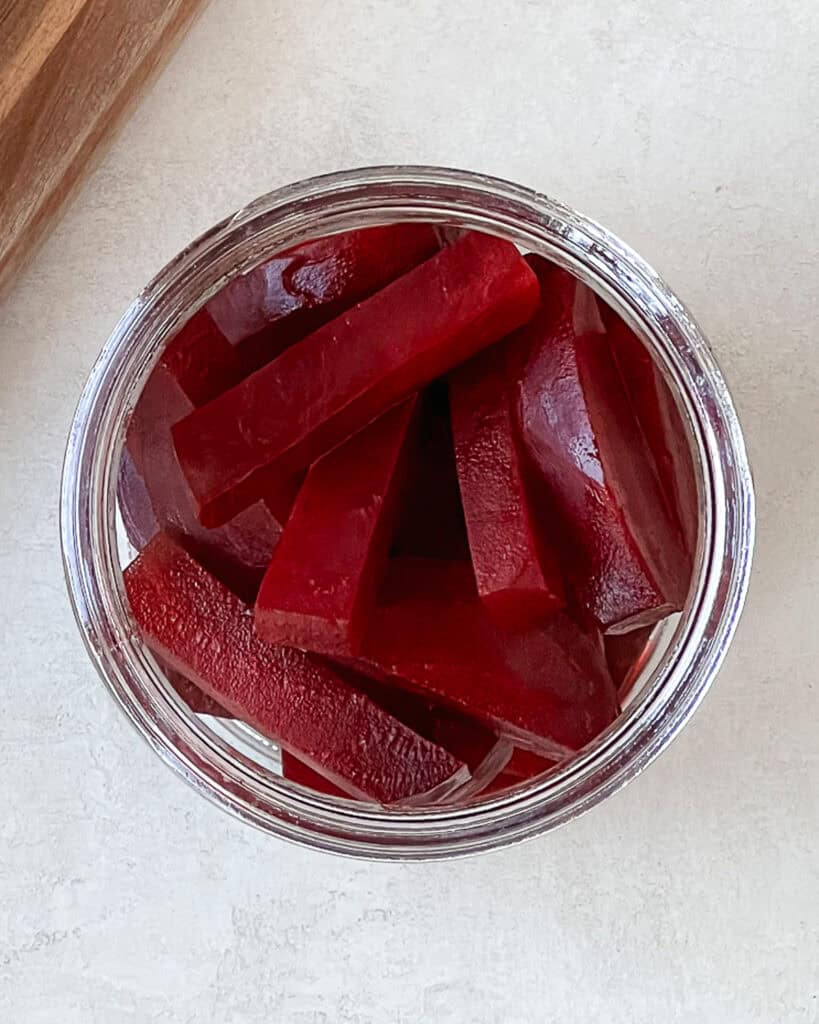 Cooked beet wedges in a glass jar.