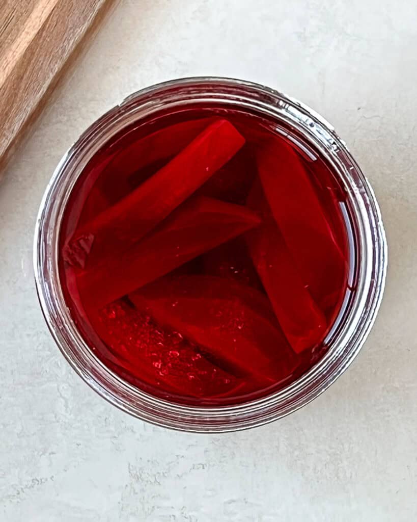 Sliced beet wedges in a glass jar submerged with vinegar brine.