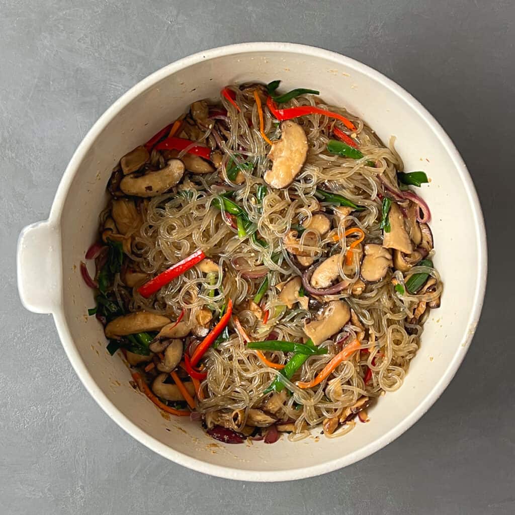 Vegan japchae toss together in a mixing bowl.