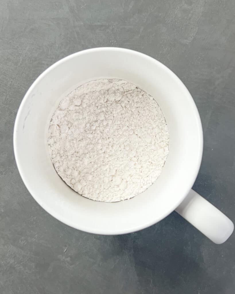Powder sugar blend with dry ingredients in a mug.