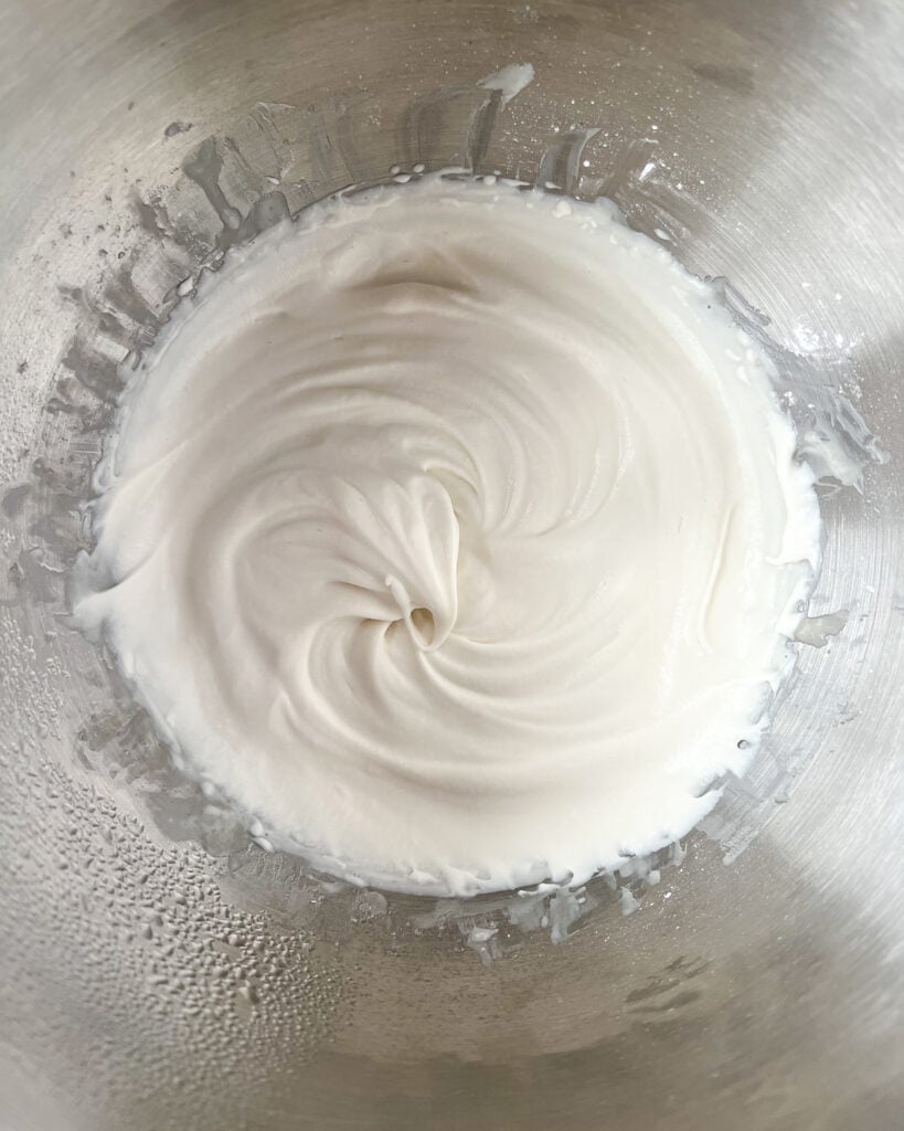 Whipped cream in a steel mixing bowl.