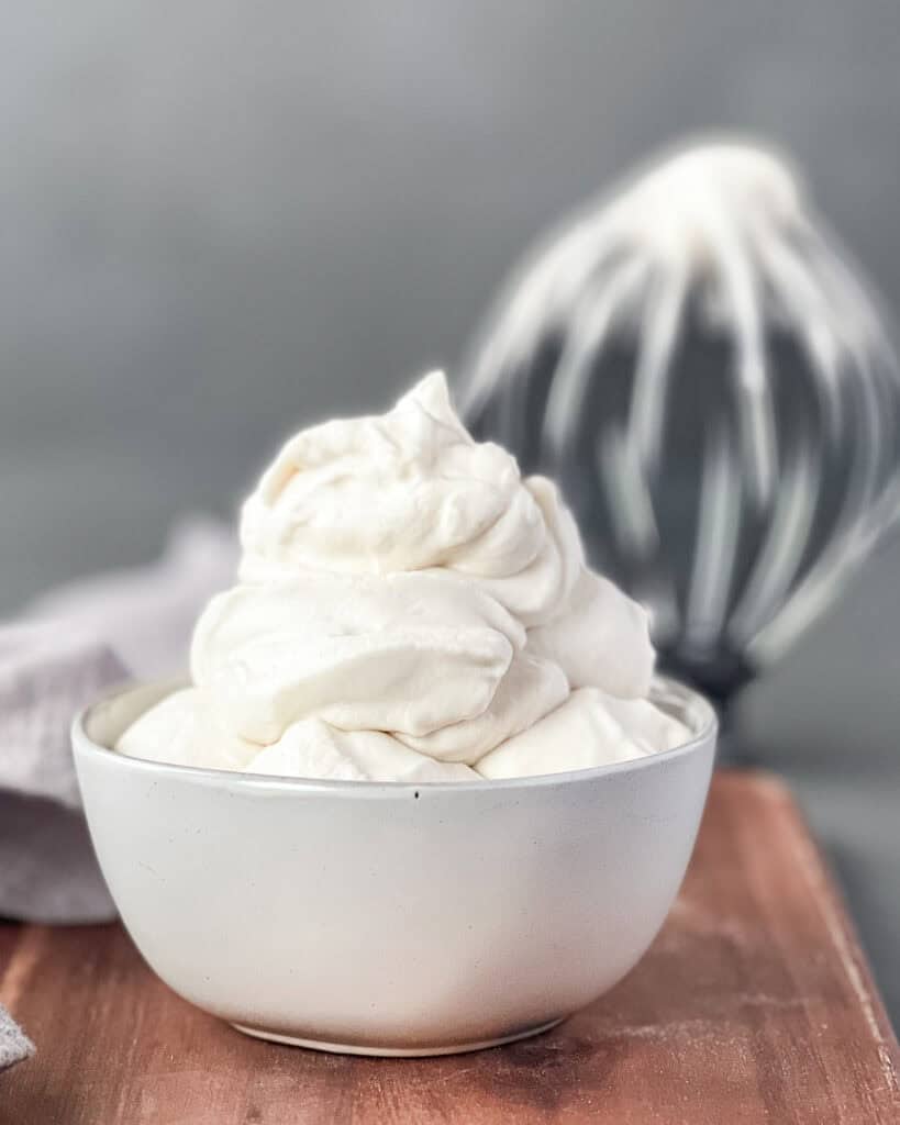 Oat milk whipped cream in a bowl over a wooden board.