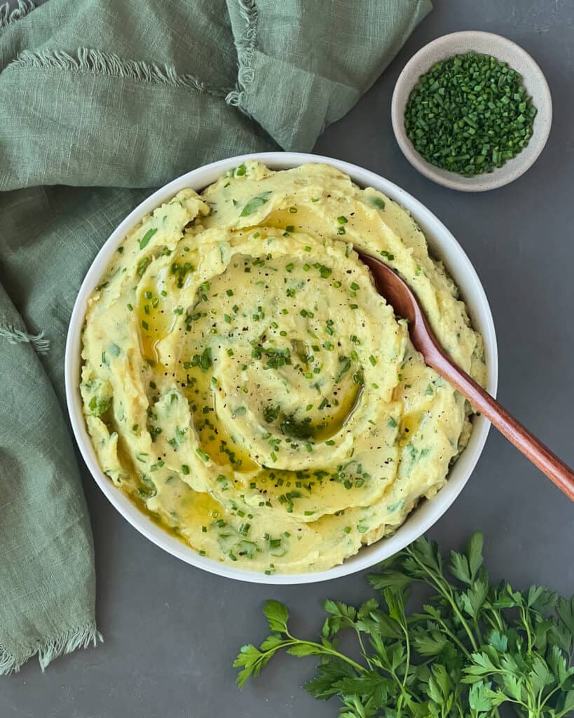 Almond milk mashed potatoes in a serving bowl with a wooden spoon in it.
