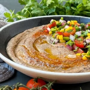 Creamy black bean hummus in a serving bowl with fresh toppings.