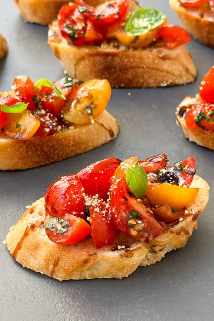 Sliced cherry tomatoes with a drizzle of balsamic glaze over toasted baguette slices.